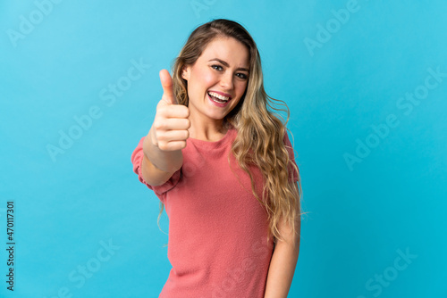 Young Brazilian woman isolated on blue background with thumbs up because something good has happened