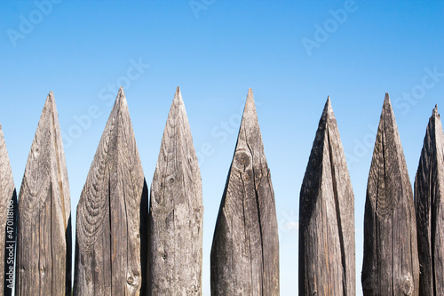 Old wooden palisade fence on blue sky background photo