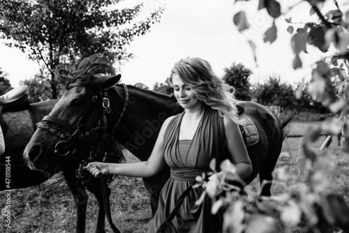 A girl in a purple dress on a walk with a horse. Black and white photo.