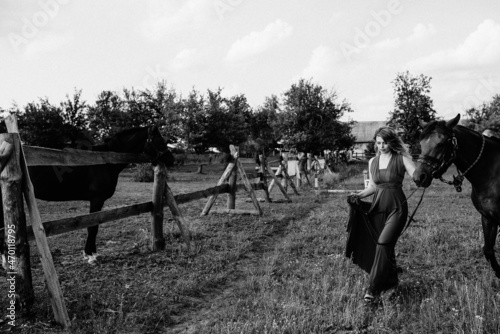A girl in a purple dress on a walk with a horse. Black and white photo.
