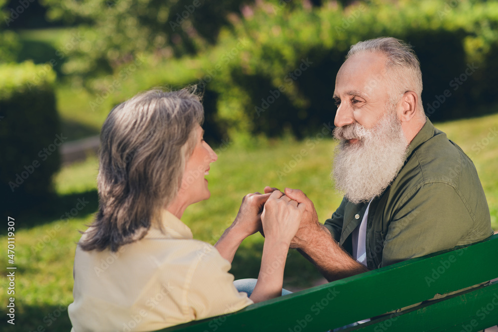 Fototapeta premium Photo of happy positive old retired people woman man sit bench hold hands nature green outdoors in urban park