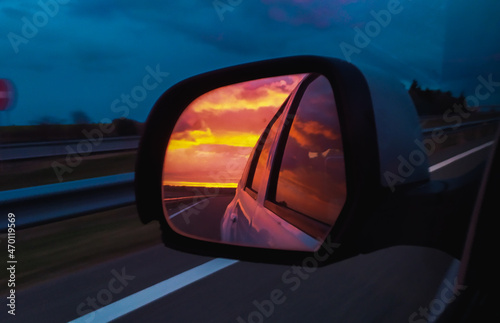 Nubes de atardecer reflejadas en el espejo retrovisor de un choche por la autopista © Alex Manzanares