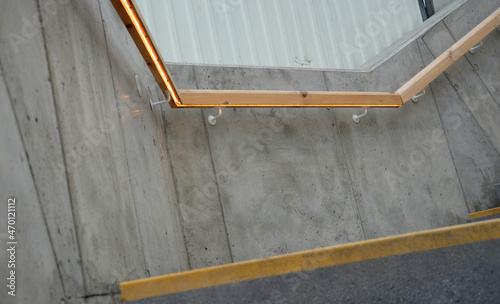from the bottom of the handle is a recessed LED strip with yellow light. hidden built-in lamp shows a man's hand. the concrete side of the staircase with retaining walls runs through terrain of slope