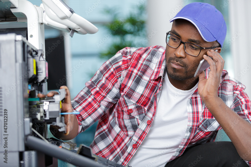 technician seeking help on the phone while repairing printer technician seeking help on the phone while repairing printer