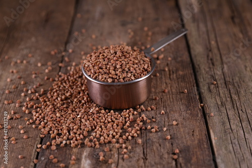 Buckwheat in a measuring glass on a wooden background
