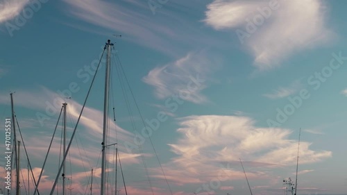 Oscillating yacht masts against the blue sky with clouds.