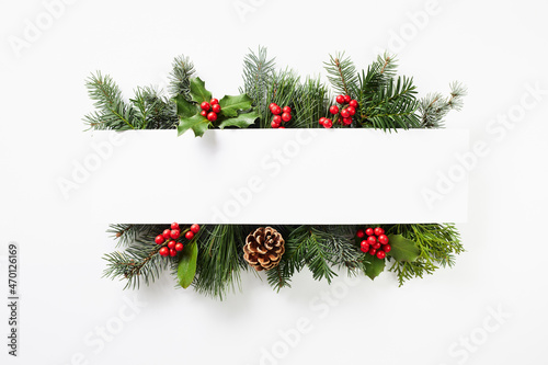 Composition of red holly berries and green branches on white background. Winter natural decoration.