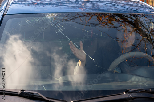 Shocked woman in car with broken windshield  and cracks. Car accident. Selective focus