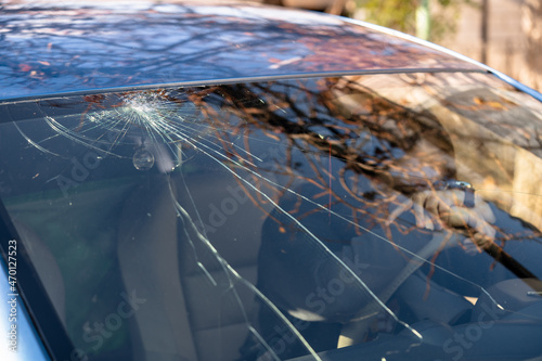 Shocked woman in car with broken windshield  and cracks. Car accident. Selective focus