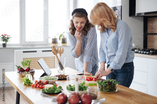 Mom and daughter cooking together in the kitchen. They use vegetables for cooking in a good mood  happy to be together
