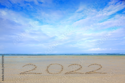 New Year 2022 written at the caribbean sand beach with sea wave .