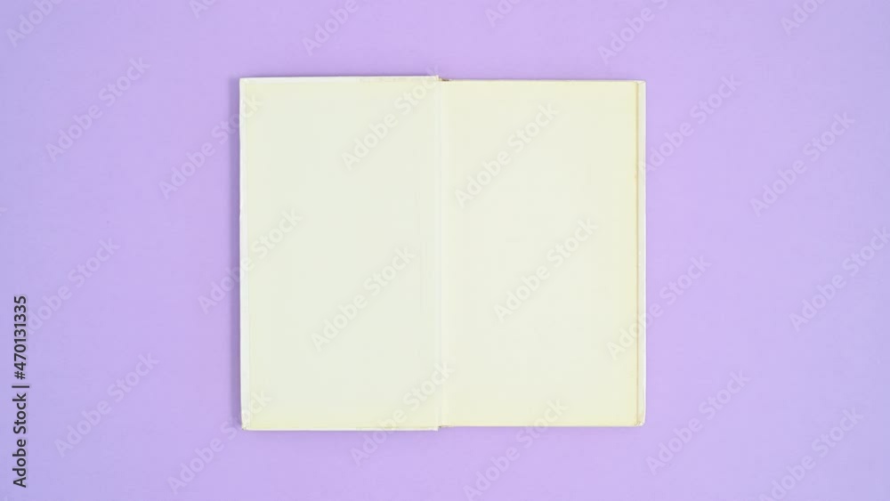 White hardcover opened book appear on purple theme, close and open again. Stop motion flat lay White hardcover opened book appear on purple theme, close and open again. Stop motion flat lay