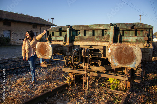 young model on railroad tracks, next to old and scrapped freight train car. © ANTONIO