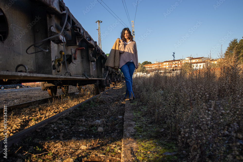 young brunette model on railroad tracks next to scrapped old freight train young brunette model on railroad tracks next to scrapped old freight train