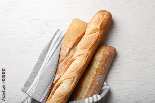 Different tasty baguettes on white wooden table, flat lay