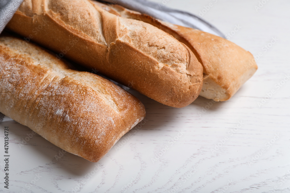 Different tasty baguettes on white wooden table, closeup