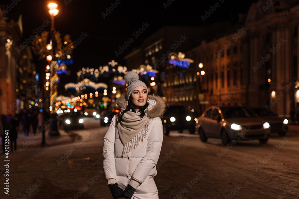 beautiful young woman in winter on the background of city lights and lights of cars