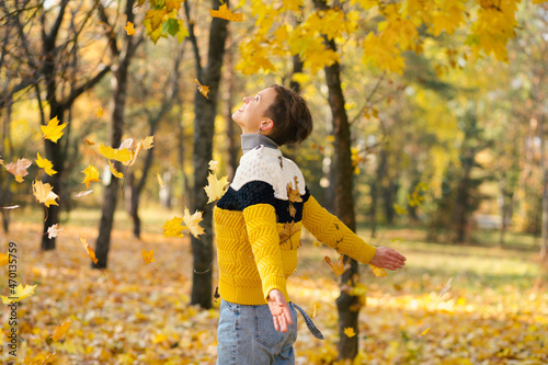 Happy young woman with short haircut spinning in the yellow falling leaves in autumn park © Veronika Kiriushina