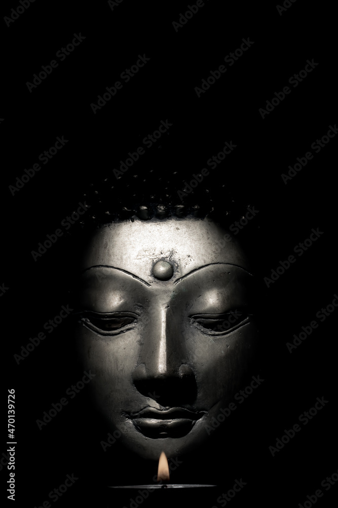 Buddha face with candle isolated over black background