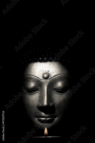 Buddha face with candle isolated over black background © Ian Dyball