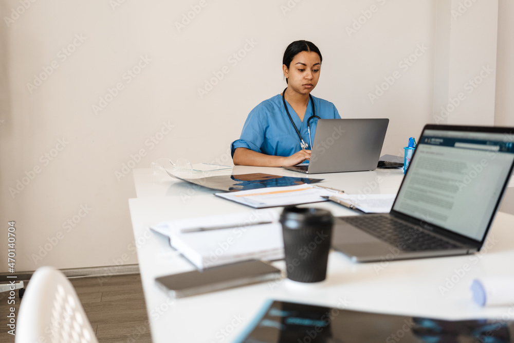 Hispanic woman doctor typing on laptop while working in office Hispanic woman doctor typing on laptop while working in office