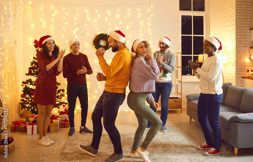 Happy millennial multiracial friends dance celebrate New Year at home party together. Smiling young diverse people have fun on Christmas festive celebration indoors. Winter holidays, friendship.