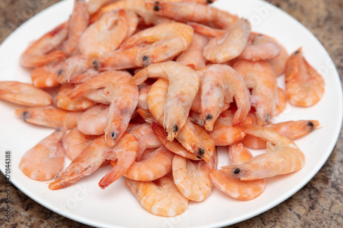 Red frozen shrimps on a white plate.