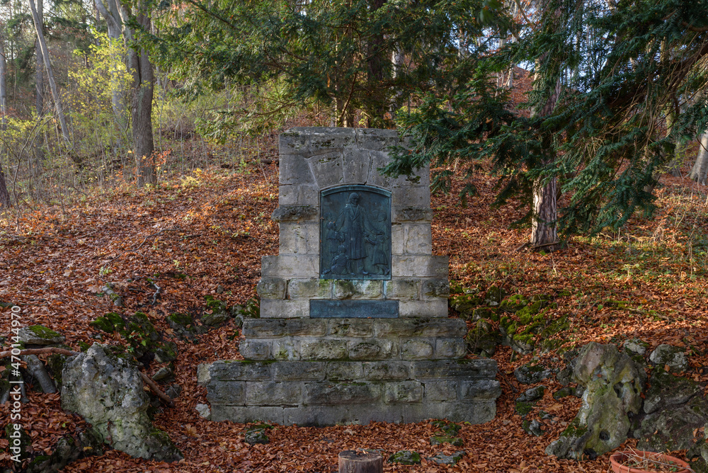 Fröbel Denkmal in Keilhau in Thüringen im Herbst umgeben von braunen Buchenblättern