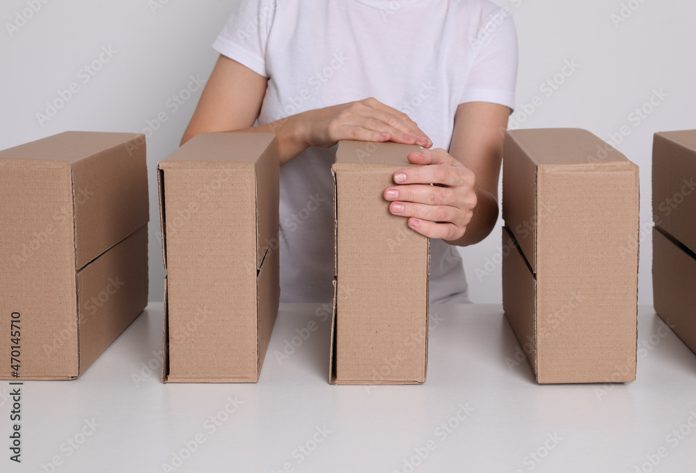 Woman folding cardboard boxes at white table, closeup. Production line Woman folding cardboard boxes at white table, closeup. Production line