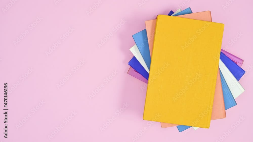 Pastel pink hardcover book appear and other pile of books ordering on it. Stop motion flat lay Pastel pink hardcover book appear and other pile of books ordering on it. Stop motion flat lay