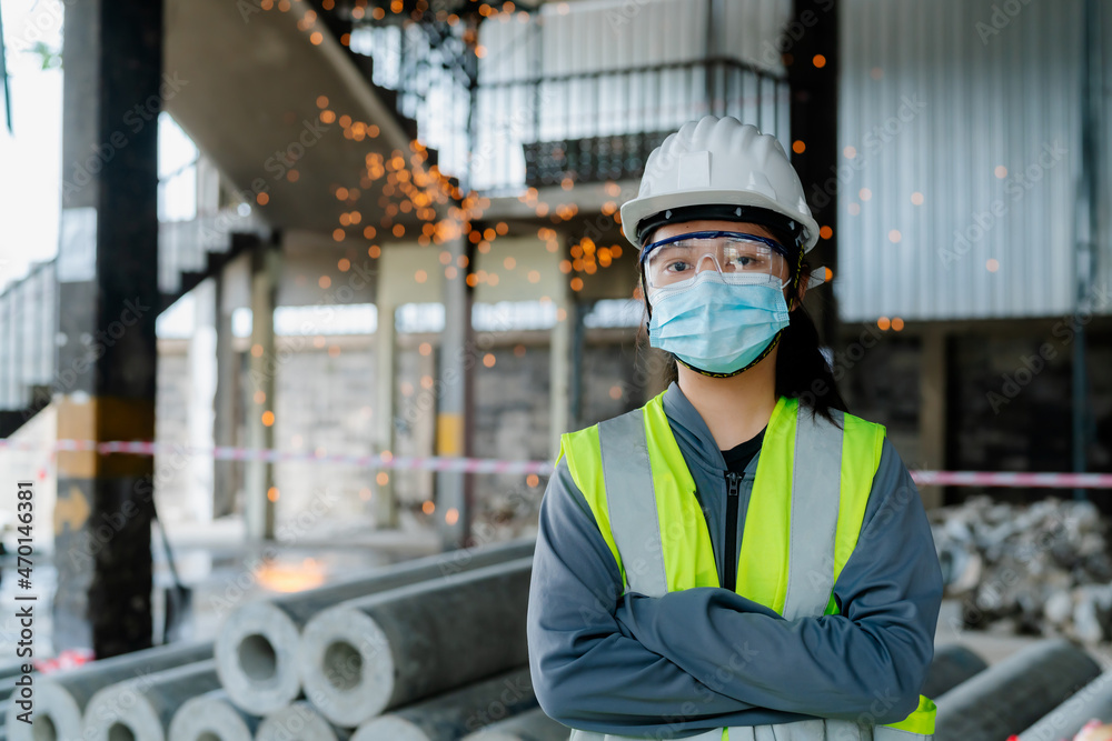 Portrait of an Asian female engineer Put on a brightly colored shirt. and wear a white safety cap standing with his arms crossed at the construction site Portrait of an Asian female engineer Put on a brightly colored shirt. and wear a white safety cap standing with his arms crossed at the construction site