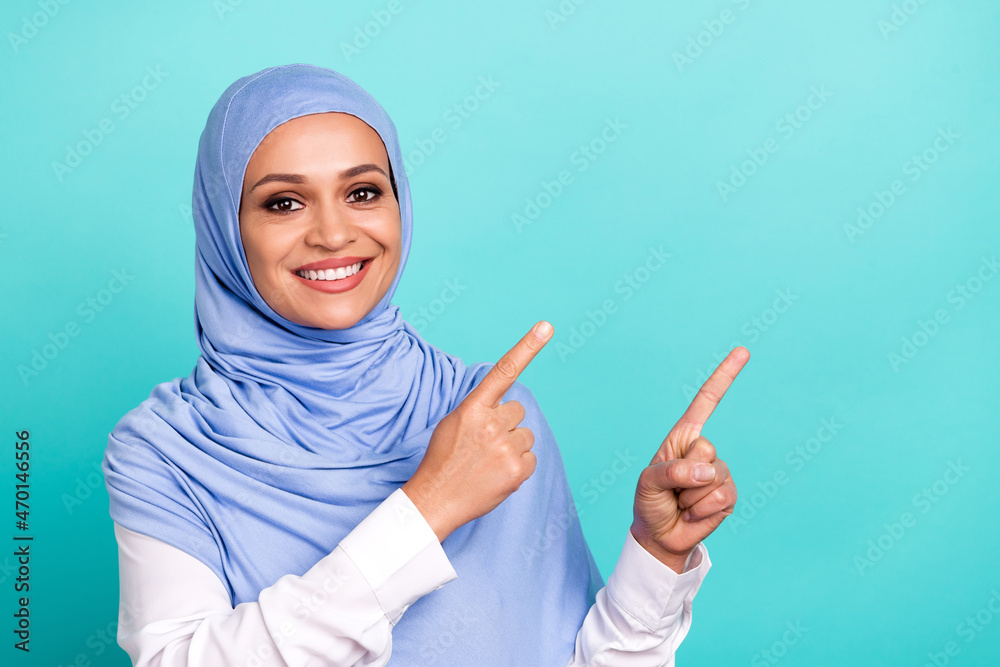 Photo of dreamy shiny young woman wear arab headscarf pointing fingers empty space smiling isolated turquoise color background Photo of dreamy shiny young woman wear arab headscarf pointing fingers empty space smiling isolated turquoise color background