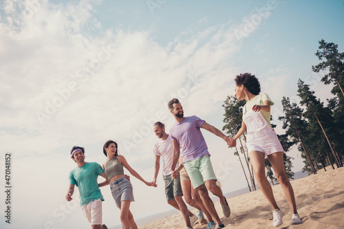 Photo of six carefree friends group people meeting hold hands walk wear casual outfit nature summer seaside beach