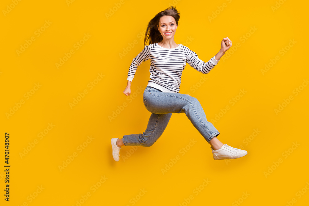 Full length profile photo of cool brunette young lady run wear sweater jeans sneakers isolated on yellow color background
