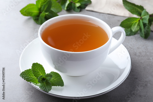 Cup of hot aromatic mint tea on light grey table