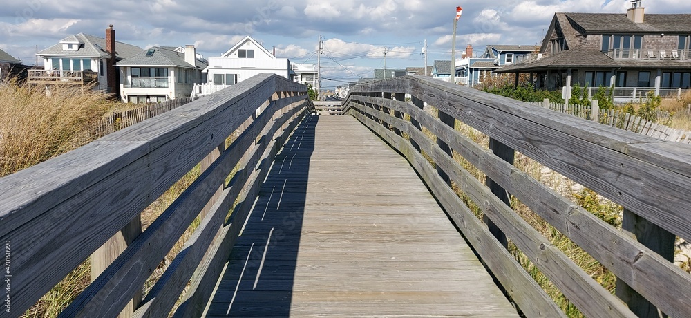 Wooden bridge over the dunes from the beach to a residential street.