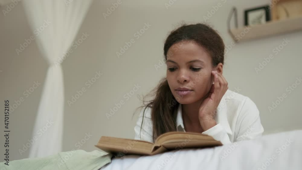 Pensive African woman reading book on the bed Pensive African woman reading book on the bed