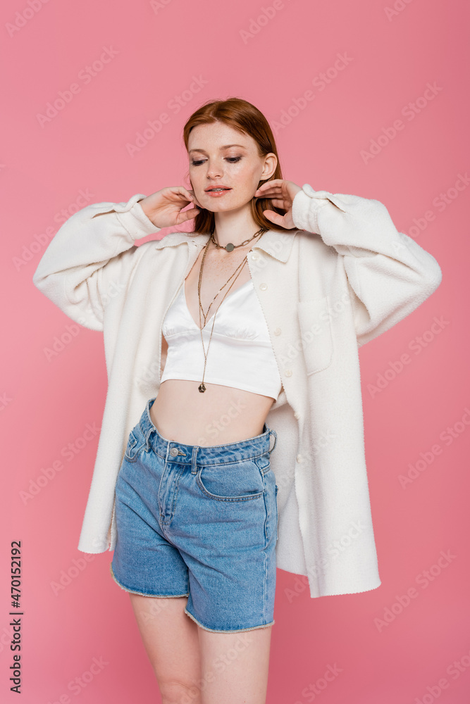 Pretty red haired woman in jacket and denim shirts posing isolated on pink Pretty red haired woman in jacket and denim shirts posing isolated on pink