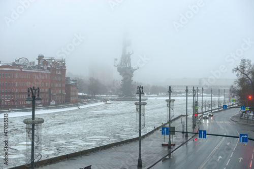 View  on the red brick building of the historic chocolate factory and the bronze monument to Peter the great on the Moscow river on a foggy winter morning. Misty winter morning in Moscow
