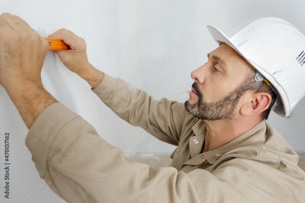 mature male builder using spirit level against the wall