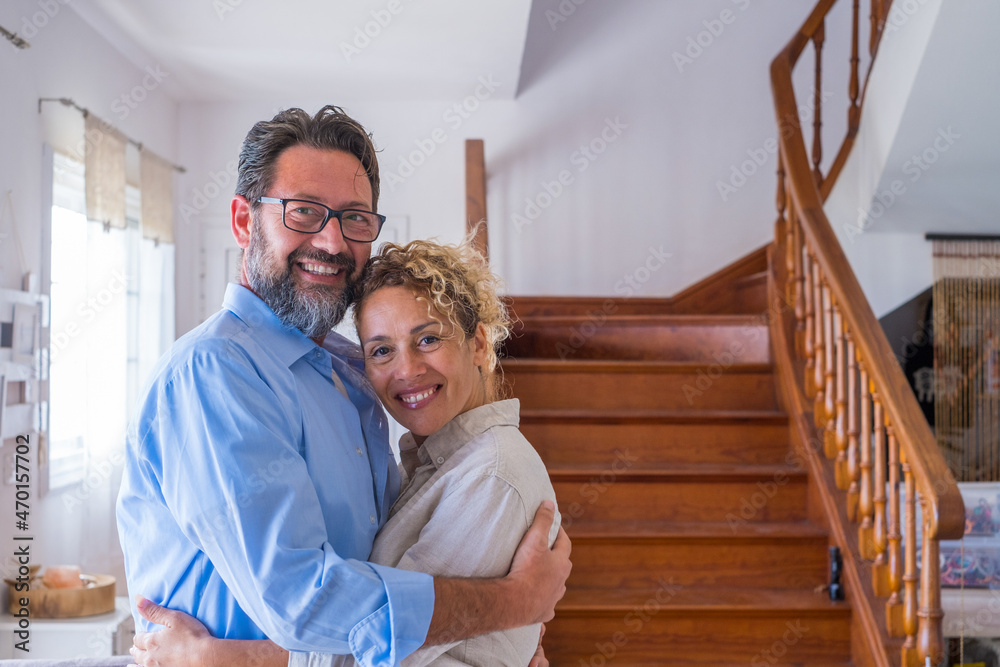 Happy caucasian couple embracing each other in the living room. Loving husband and wife hugging at home. Profile of affectionate man and woman spending leisure time together at modern house Happy caucasian couple embracing each other in the living room. Loving husband and wife hugging at home. Profile of affectionate man and woman spending leisure time together at modern house