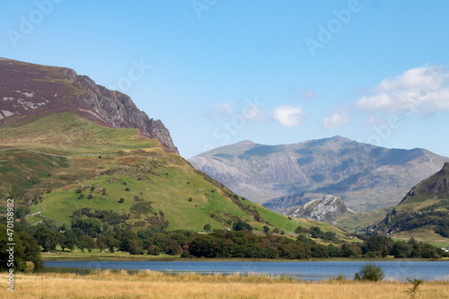 Beautiful lake Nantlle, Snowdonia, Wales. Panorama with foreground of water and meadow. Dramatic, rugged Mount Snowdon in the background. Landscape aspect view with copy space.