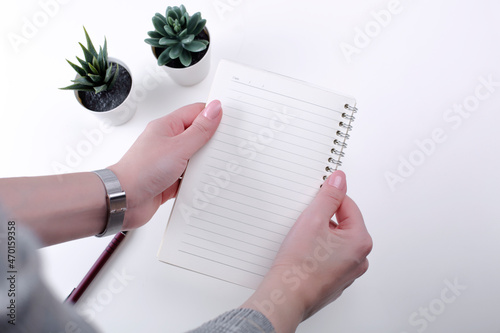 Wallpaper Mural Woman writes in the planner. Overhead view of female hands holding white notebook mockup on white desk. Torontodigital.ca