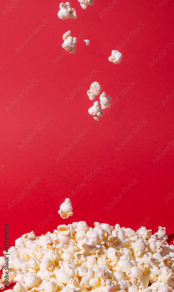 A bunch of popcorn, popcorn falling on a red background. Holidays, cinema time concept. Minimal style. A bunch of popcorn, popcorn falling on a red background. Holidays, cinema time concept. Minimal style.