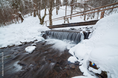 Winter mountain waterfall snow scene. Snowy mountain waterfall landscape. Winter mountain waterfall in Shipot waterfall - Carpathian Mountains, Ukraine. photo