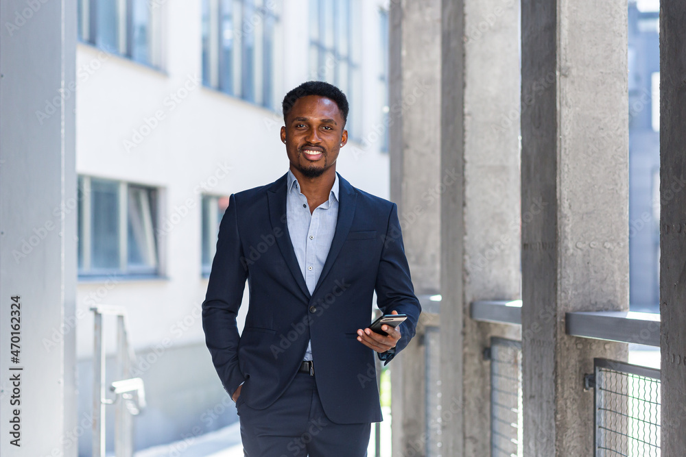 Successful african american businessman smiles and looks at camera, happy uses phone and keeps thumbs up Successful african american businessman smiles and looks at camera, happy uses phone and keeps thumbs up