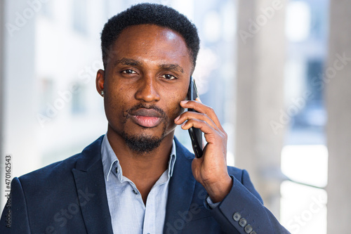 Portrait of an African American businessman talking seriously on the phone and looking at the camera, close-up photo of a man in a business suit using the phone