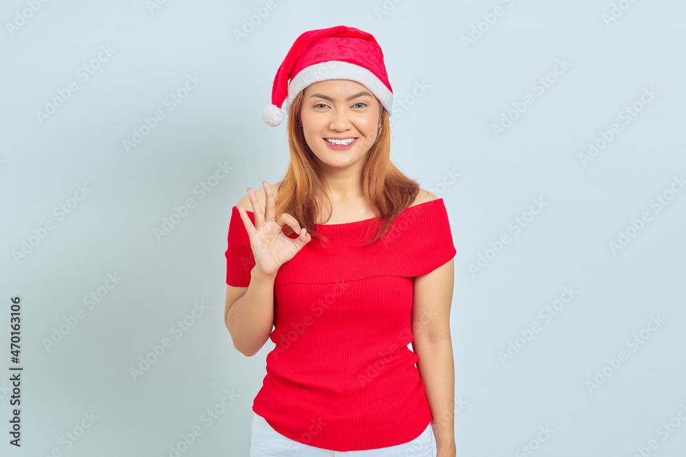 Portrait of beautiful smiling Asian woman wearing christmas dress and showing gesturing okay sign on white background Portrait of beautiful smiling Asian woman wearing christmas dress and showing gesturing okay sign on white background