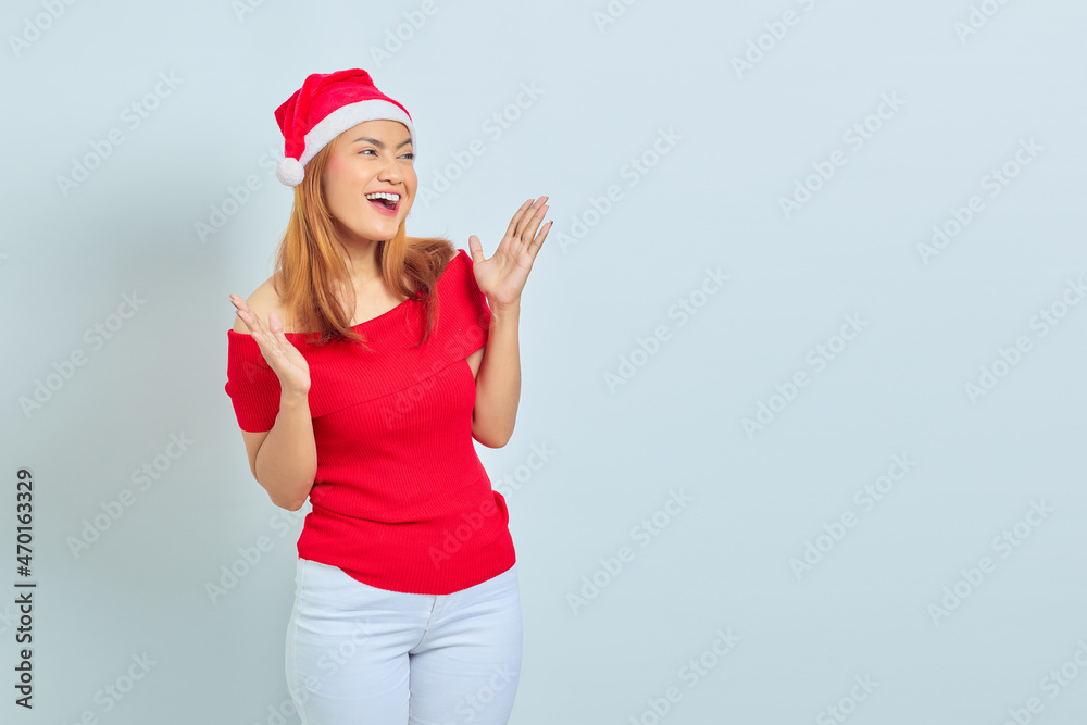 Beautiful young Asian woman wearing christmas dress showing cheerful and excited face over white background Beautiful young Asian woman wearing christmas dress showing cheerful and excited face over white background