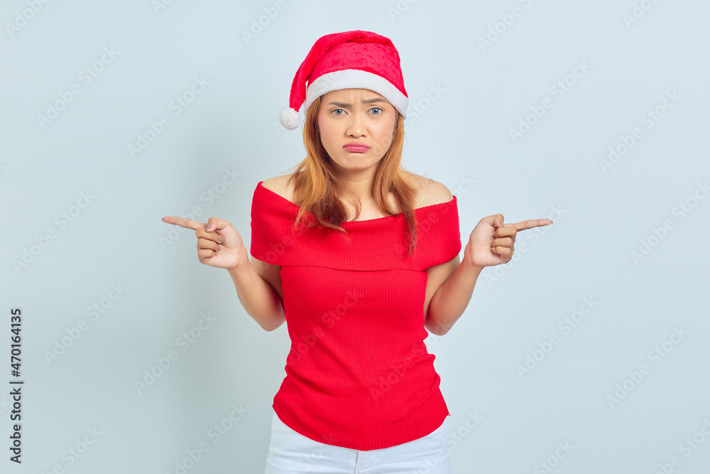 Portrait of young Asian woman wearing christmas dress pointing to the laterals having doubts Portrait of young Asian woman wearing christmas dress pointing to the laterals having doubts